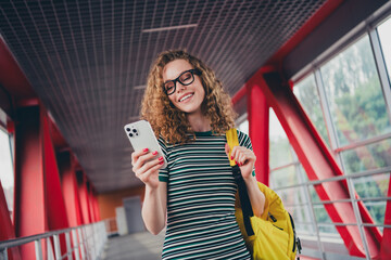 Portrait of nice young girl use phone backpack striped dress work study office business center