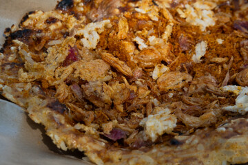 Kerak telor, a traditional street food from Jakarta, Indonesia. This food is an omelet with rice, served with fried grated coconut. Sold on a street stall