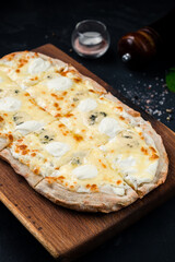 Italian food pizza or pinza with different types of cheese on wooden board.