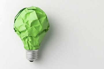 A crumpled green paper light bulb on a brown background