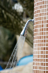 Shower on the beach. Closeup of outdoor shower head. Outdoor pool shower. Water running from poolside shower sprinkler