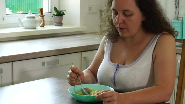 Woman eats soup with meatballs