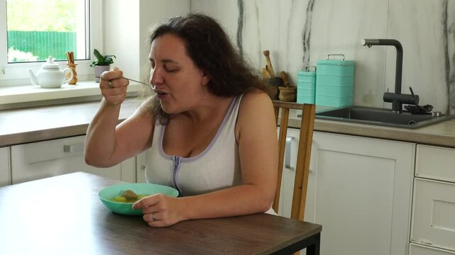 Woman eats soup with meatballs