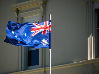 The Australian flag, a vibrant symbol of the nation, flutters proudly in the wind against a...