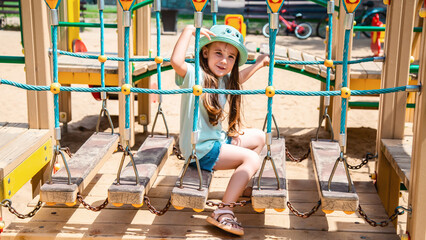 A cute little girl is playing in the children's yard. Healthy summer fun for kids. Child girl...