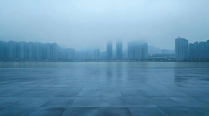 An empty paved square with a cityscape shrouded in fog in the background.