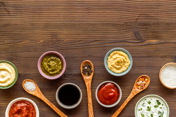 Set of sauces in bowls with spices in spoons and ingredients, top view
