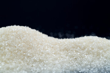 Pile of white sugar crystals on black background