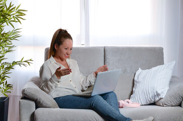 European woman, teleworking on the sofa at home, happy