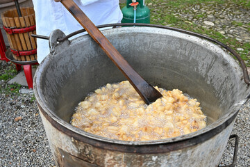 Ciccioli di maiale or pork cracklings cooked in their own fat in a large pot in Italy in Zibello