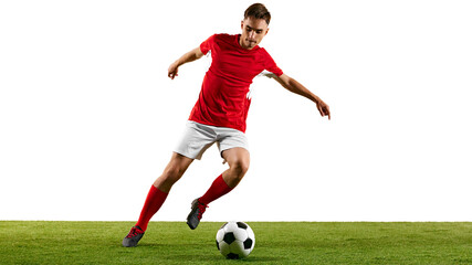 Athletic football player in red-white uniform, practicing dribbling on green pitch, training to master footwork and agility against white background. Concept of championship, sport events, final game