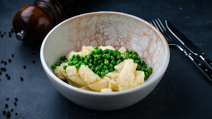 Boiled mashed potatoes with green peas in a plate.