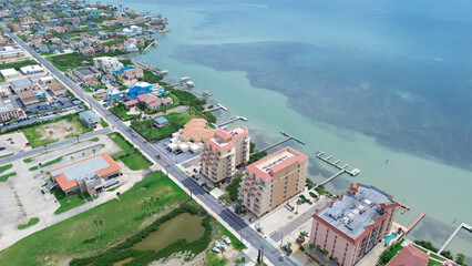 Private jetty boat access waterfront beach condos, hotels, high-rise apartment, vacation rentals of tropical South Padre Island, Texas, dense of sargassum black seaweed along Laguna Bay, aerial © trongnguyen