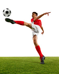 Naklejka premium Dynamic photo of football player focuses on powerful kick during training on green field against white background. Game-winning skills. Concept of championship, sport events, final game. Ad