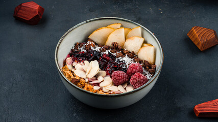 Granola bowl with raspberries, pears, almonds, coconut and berry jam.