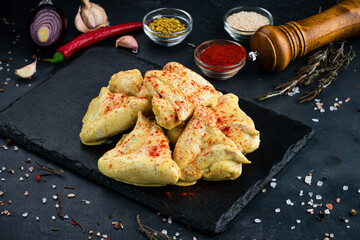 Portion marinated barbecue chicken thighs in mustard sauce and paprika on a dark background.