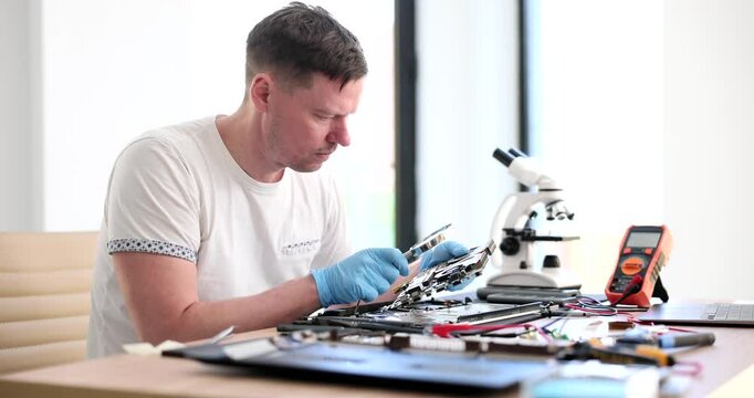 Specialist computer maintenance engineer analyzing laptop hardware through magnifying glass. Repair and diagnostics of computer equipment