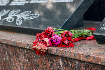 A beautiful bunch of vibrant red and pink flowers rests on a granite ledge