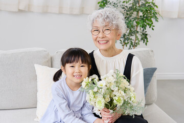 花束を持つ祖母と孫　リビング　カメラ目線