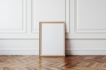 Empty wooden frame leaning against a white paneled wall on a herringbone wooden floor. Classic and minimalist interior design concept for art display and print