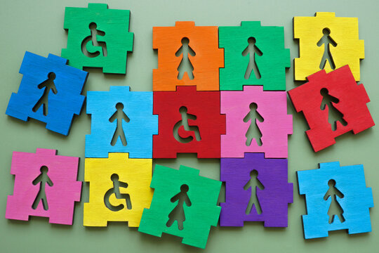 Colorful puzzle pieces with male, female figures and disability sign representing inclusion and diversity.