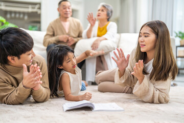 Asian father and mother with daughter bonding time, learning and reading book together on floor, family education at home, nurturing childhood development, happy love asian family indoors, lifestyle