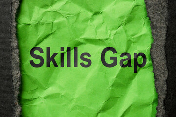 Torn paper with the phrase skills gap. Workforce development concept.