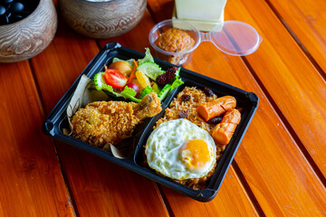 American fried rice with sausages, fried egg, fried chicken, cucumber and tomatoes,Thai style