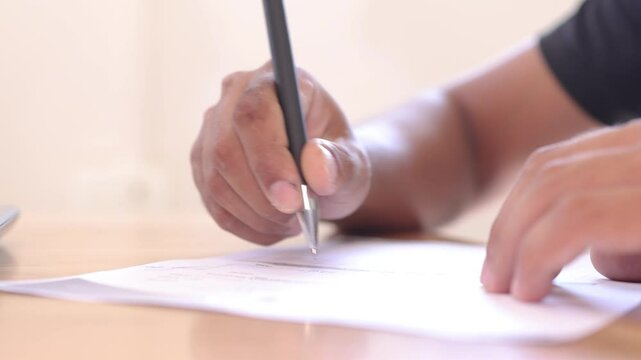close up of a male or man  writing on a paper using a pen