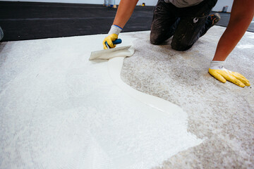 Construction worker spreading self leveling concrete on the floor