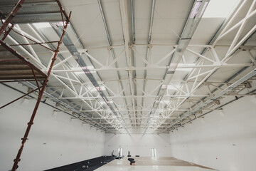 Construction workers installing floor insulation and vapor barrier in large warehouse