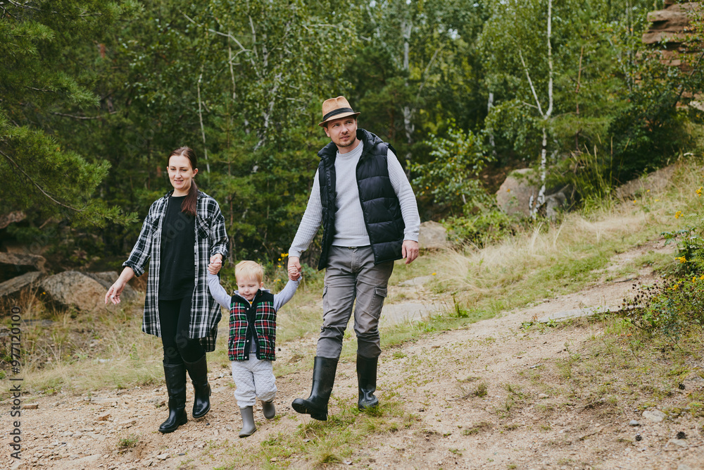 Wall mural Happy family on a walk in the forest picking berries and herbs, traveling along paths and stones mom dad and children