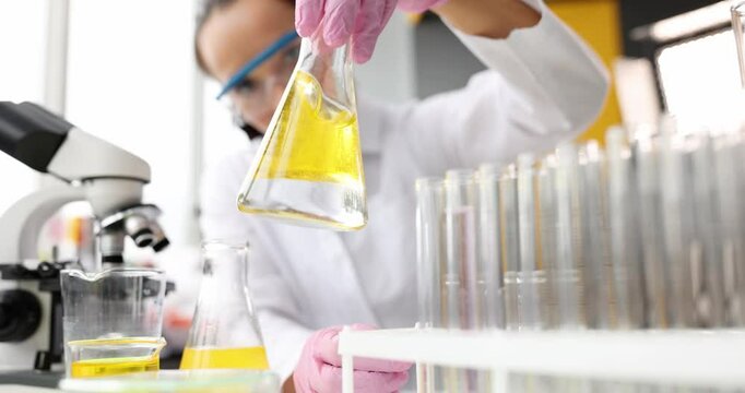 Scientist conducts chemical experiment in flask with oil. Toxic and poisonous solvent concept
