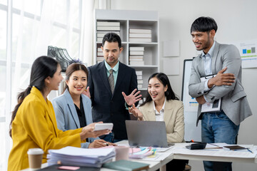 A group of people are gathered around a table with a laptop, smiling