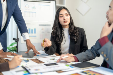 A woman in a business suit is pointing at a presentation on a table