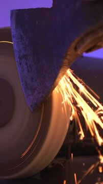 vertical video close up of sharpening an axe on a machine with a grinding stone