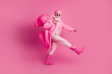 Full size profile photo of extravagant man carry christmas bag walk wear hat coat boots isolated on pink color background