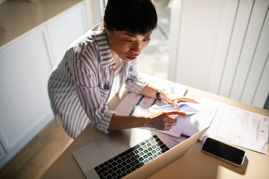 Focused woman organizing bills and paperwork in kitchen