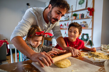 Family baking Christmas cookies together in festive kitchen with Christmas tree