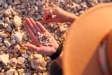 girl relaxing on the beach. a girl sits on the beach and collects various shells in her hand. hands with shells close-up.