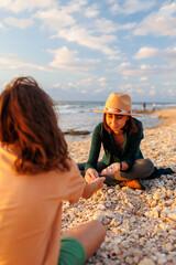 boy collects shells and pebbles in the sea on a sandy beach with his mother. Family having fun on the beach collecting shells.