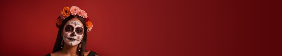 Mexican woman traditional sugar skull make up, national costume and marigold crown for Dia de los Muertos celebration. Wide red banner with copy space. Day of Dead latin culture festival concept 