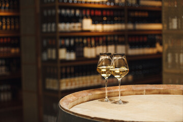 Two Glasses of White Wine on Wooden Barrel in Wine Cellar with a Free Copy Space