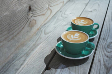 Two beautiful cups with delicious double cappuccino in the morning light. Beautiful latte art. Perfect photo for coffee shops, coffee lovers and cafe. Copy space for the text.