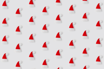 Pattern of red Santa Claus hat on white background, top view. Christmas minimalist concept