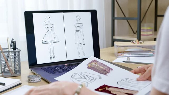 Female fashion designer working with clothes sketches drawn on paper using laptop. Seamstress concept.