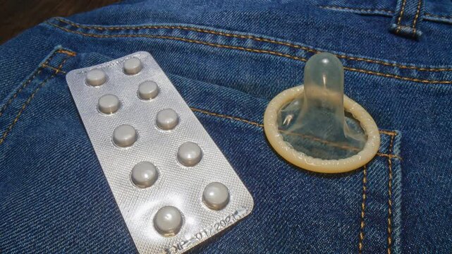 Condom and contraception pills on jeans. Comparison of sexual contraception.
