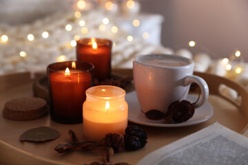 Burning candles, lights, coffee and decor on bed indoors, closeup. Autumn atmosphere