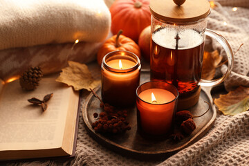 Burning candles, freshly brewed tea, sweaters, book and autumn decor on fabric
