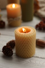 Autumn atmosphere. Burning candle, pinecones and acorn on grey wooden table, closeup